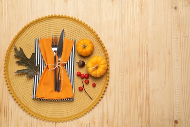 Cutlery, napkins and autumn decoration on wooden background, flat lay with space for text. Table setting