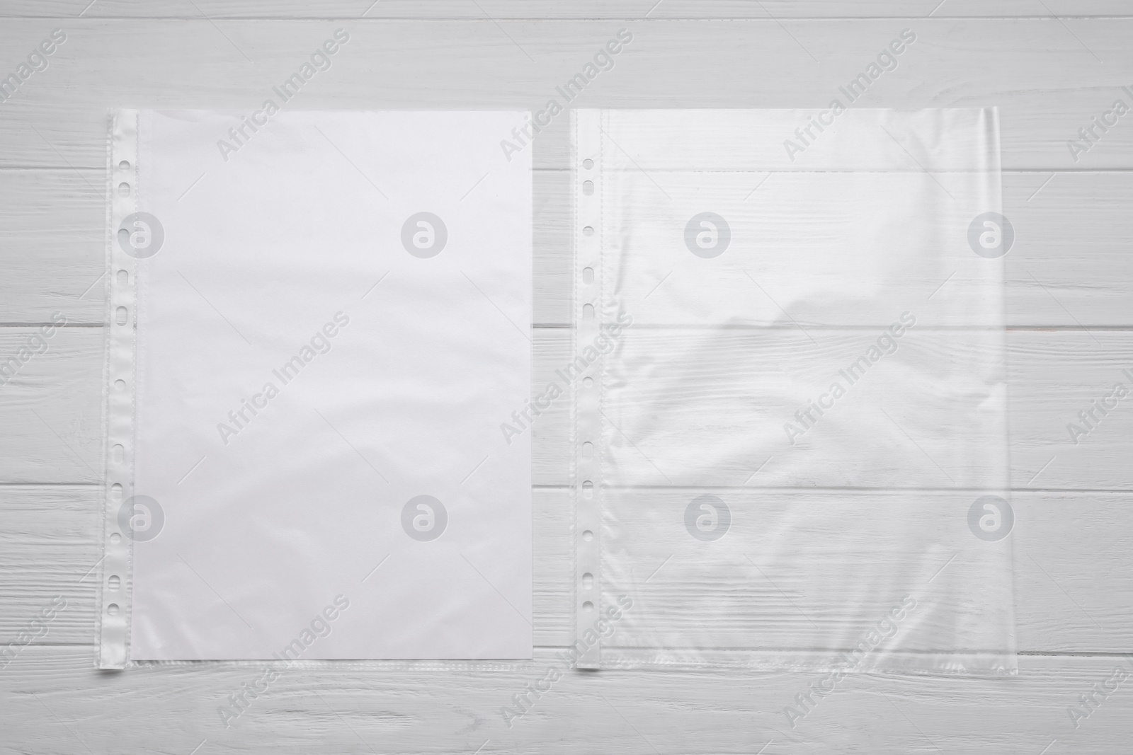 Photo of Punched pockets on white wooden table, flat lay. Space for text