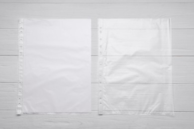 Photo of Punched pockets on white wooden table, flat lay. Space for text