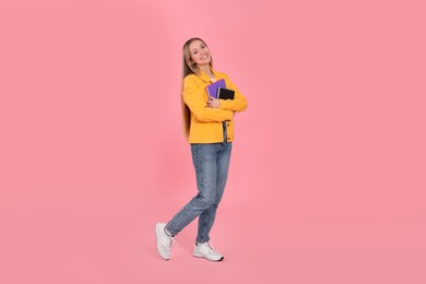 Teenage girl with notebooks on pink background