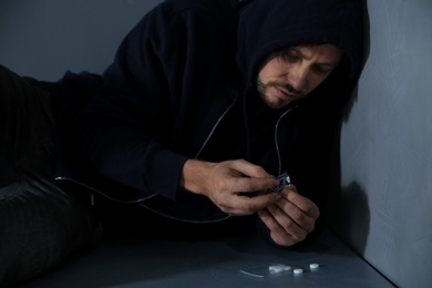 Photo of Young addicted man with drugs lying on floor