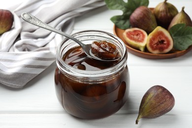 Photo of Jar of tasty sweet jam and fresh figs on white wooden table