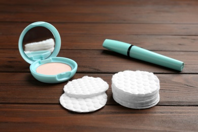 Composition with cotton pads, powder and mascara on wooden background