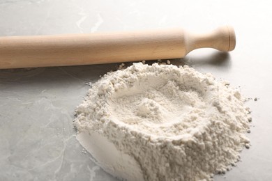 Pile of flour and rolling pin on grey marble table, closeup