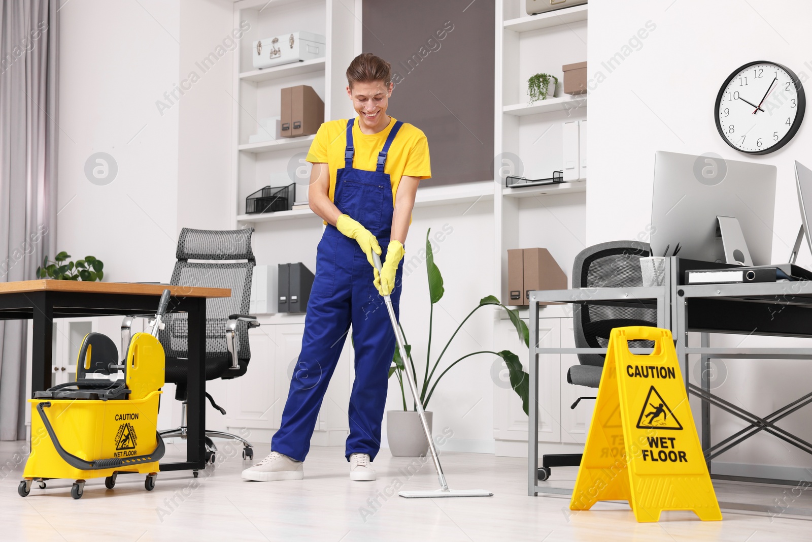 Photo of Cleaning service. Man washing floor with mop in office