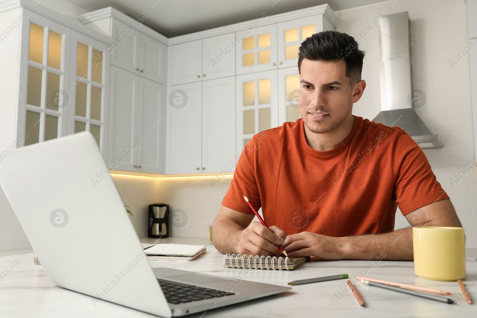 Photo of Man drawing in notebook at online lesson indoors. Distance learning