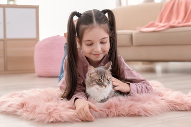 Photo of Cute little girl with cat lying on floor at home