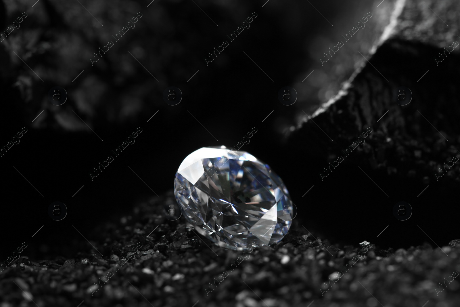 Photo of Beautiful shiny diamond on decorative black sand