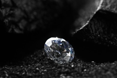Photo of Beautiful shiny diamond on decorative black sand