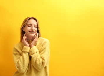 Photo of Beautiful young woman wearing knitted sweater on yellow background. Space for text