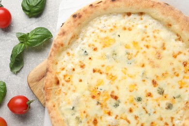 Photo of Delicious cheese pizza, basil and tomatoes on light grey table, flat lay