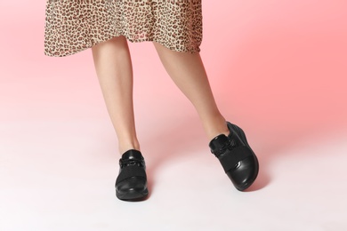 Woman in dress and stylish shoes on color background, closeup