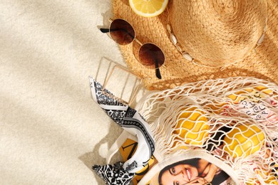String bag with fashion magazine, fresh lemons and accessories on beige textured background, flat lay. Space for text