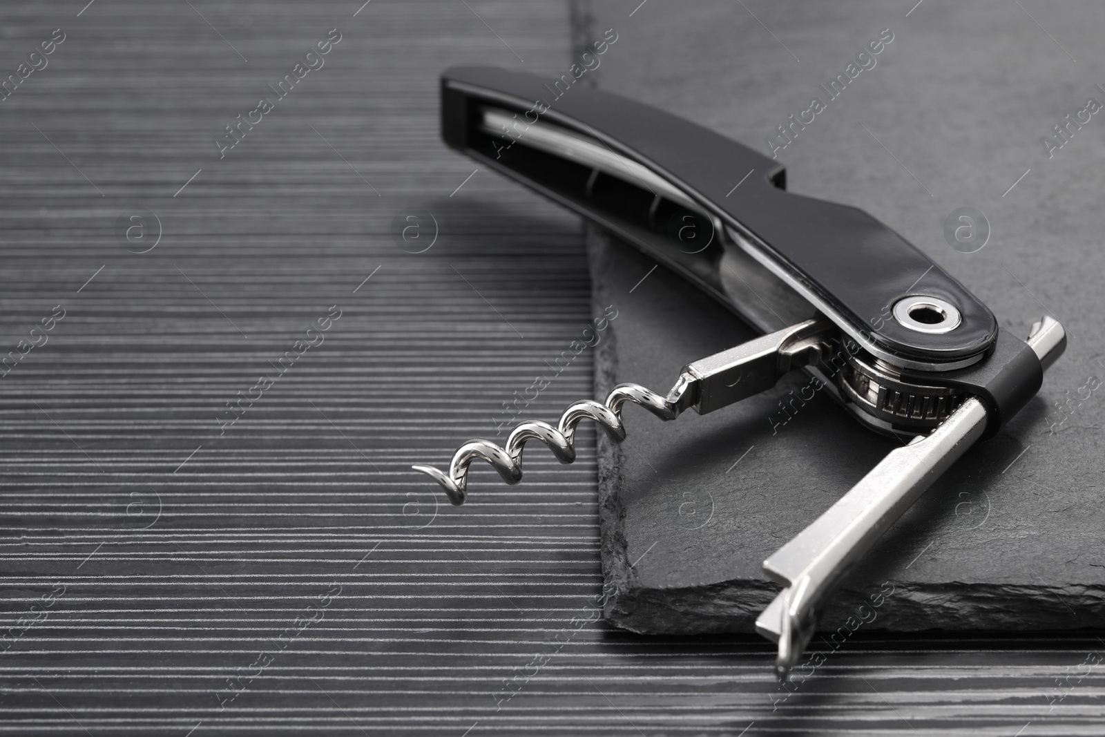 Photo of One corkscrew (sommelier knife) on black wooden table, closeup. Space for text