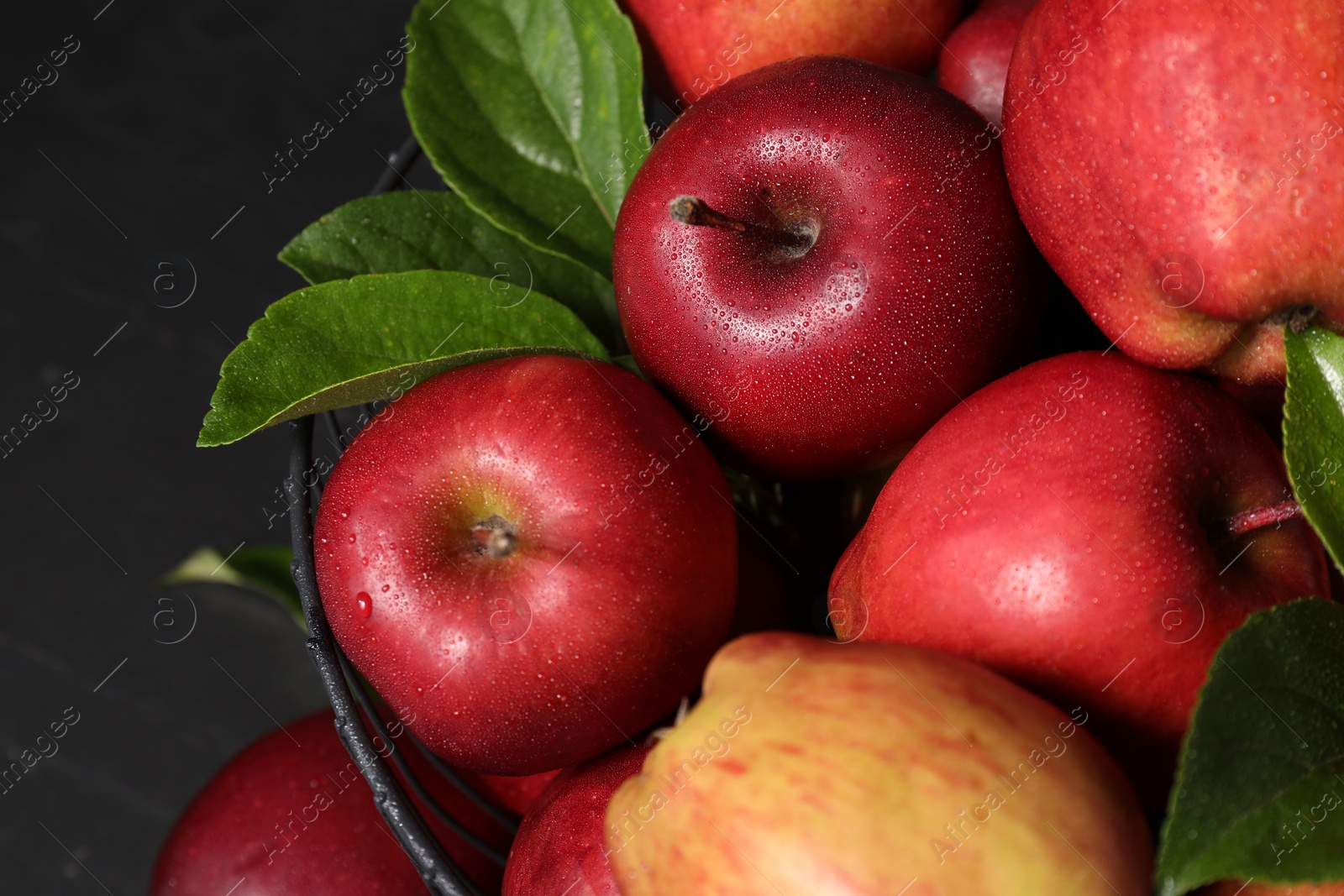 Photo of Fresh ripe red apples with water drops in metal bowl on dark grey table, closeup