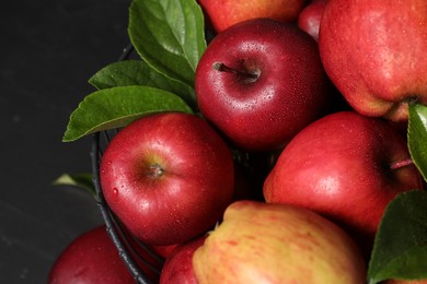 Fresh ripe red apples with water drops in metal bowl on dark grey table, closeup