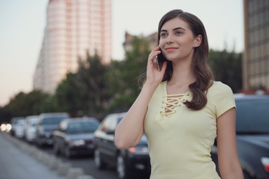 Photo of Beautiful young woman talking on phone outdoors