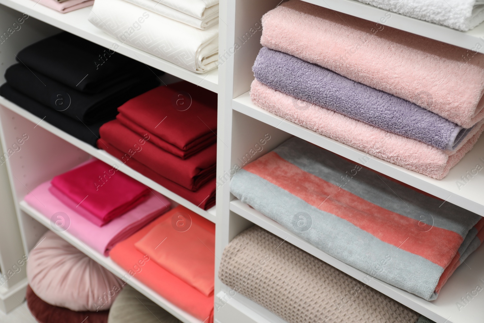 Photo of Different color linens on shelves in shop