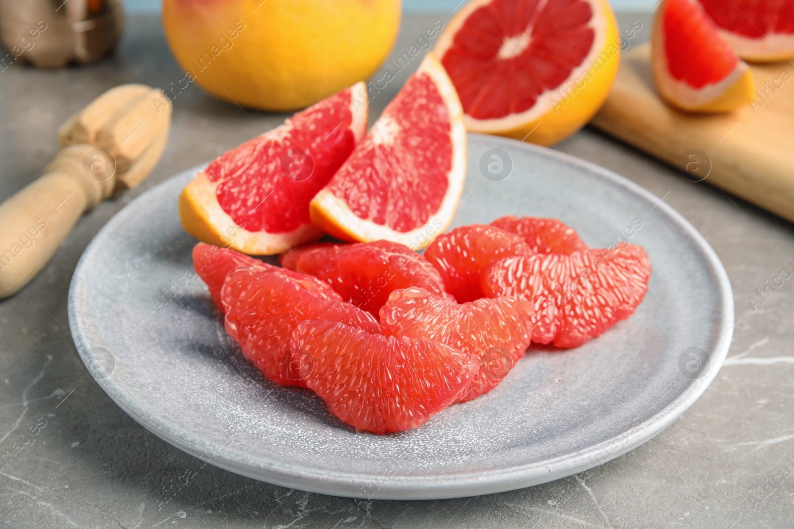 Photo of Plate with ripe grapefruit on grey table