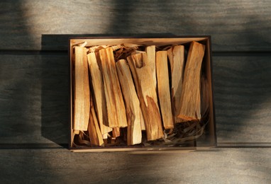 Box of many palo santo sticks on wooden table, top view