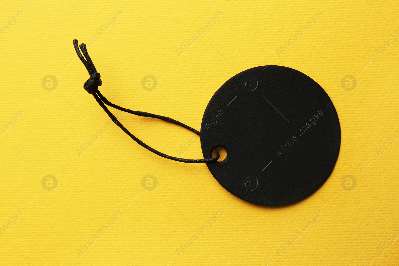Photo of Circle shaped tag with space for text on yellow background, top view