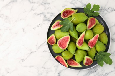 Cut and whole green figs on white marble table, top view. Space for text