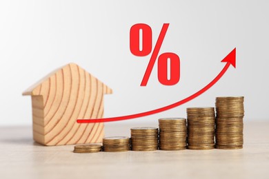 Image of Mortgage rate. Wooden model of house, stacked coins, arrow and percent sign