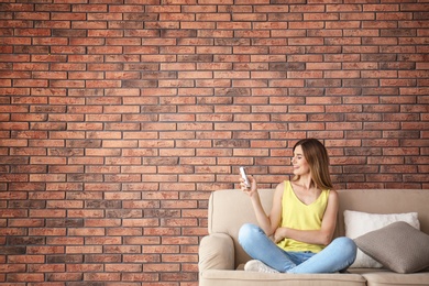 Photo of Woman with air conditioner remote at home