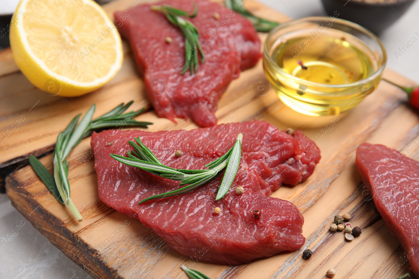 Photo of Fresh raw meat steaks and spices on wooden board, closeup