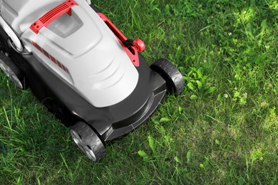 Photo of Cutting green grass with lawn mower in garden, top view. Space for text