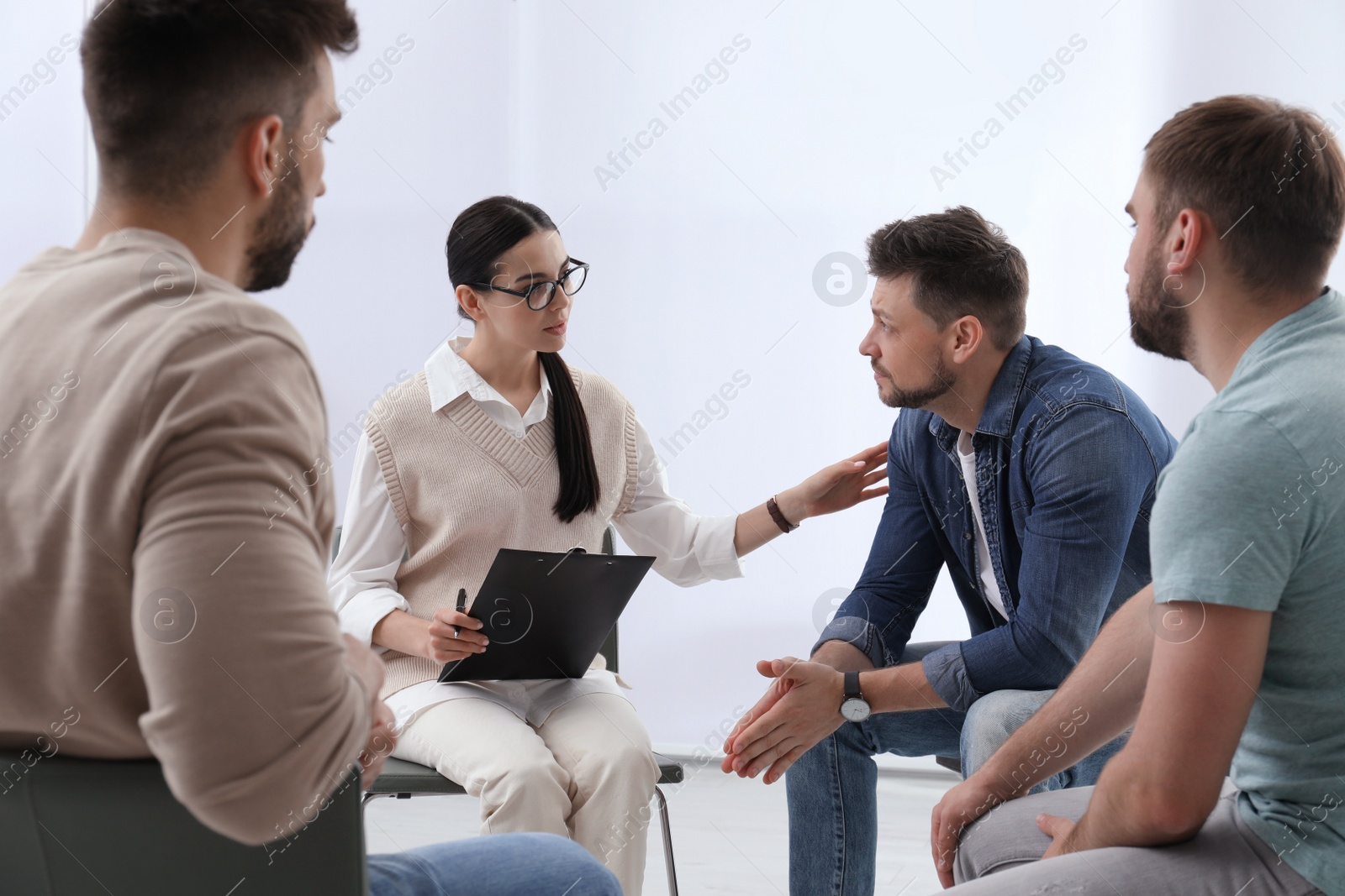 Photo of Psychotherapist working with group of drug addicted people at therapy session indoors