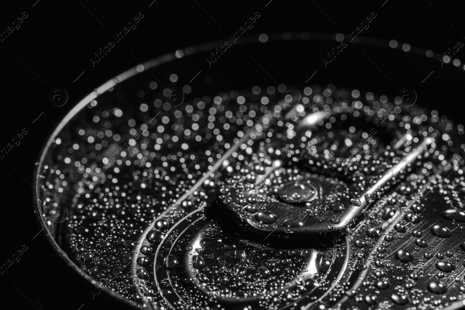 Photo of Aluminum can of beverage covered with water drops on black background, closeup