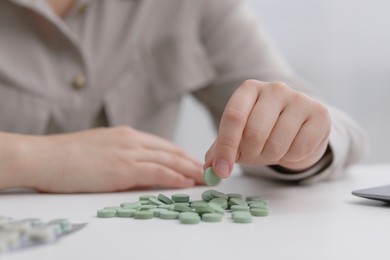 Photo of Woman with antidepressant pills at white table, closeup