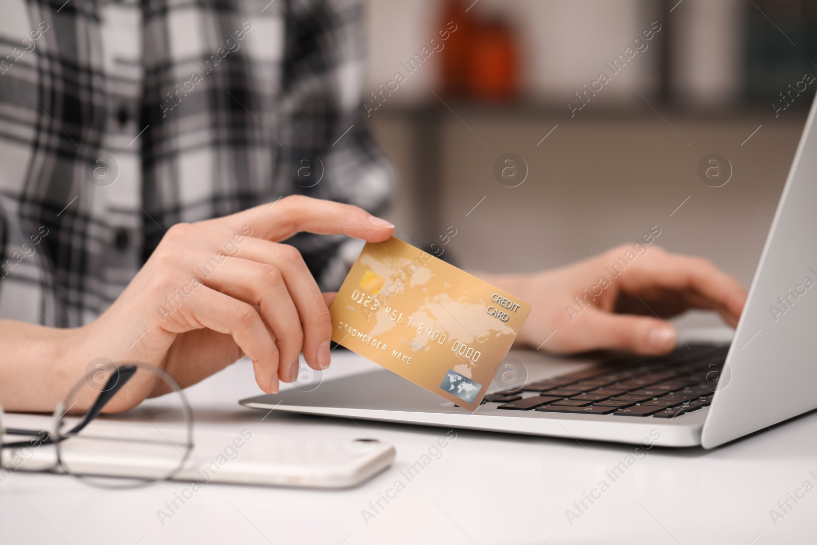 Photo of Woman with credit card using laptop for online shopping at white table, closeup