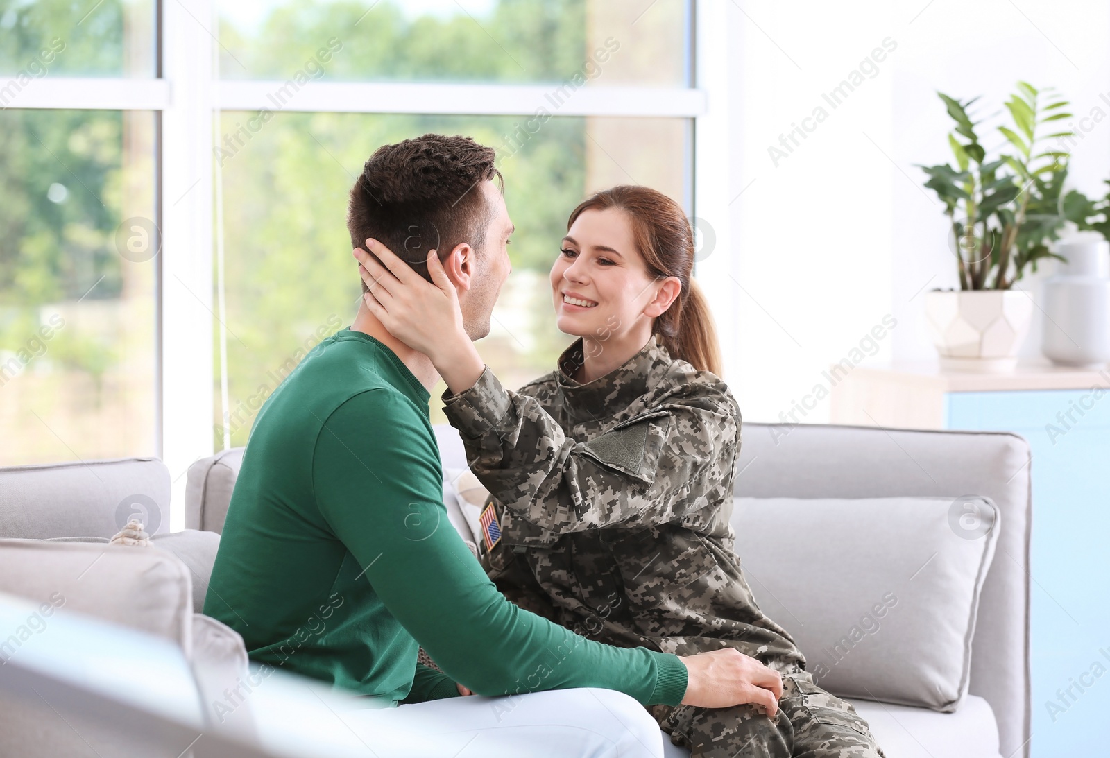 Photo of Woman in military uniform with her husband on sofa at home