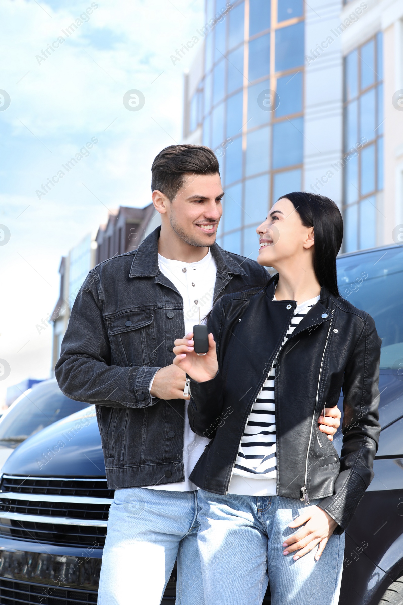 Photo of Happy couple with key near car on city street. Buying new auto