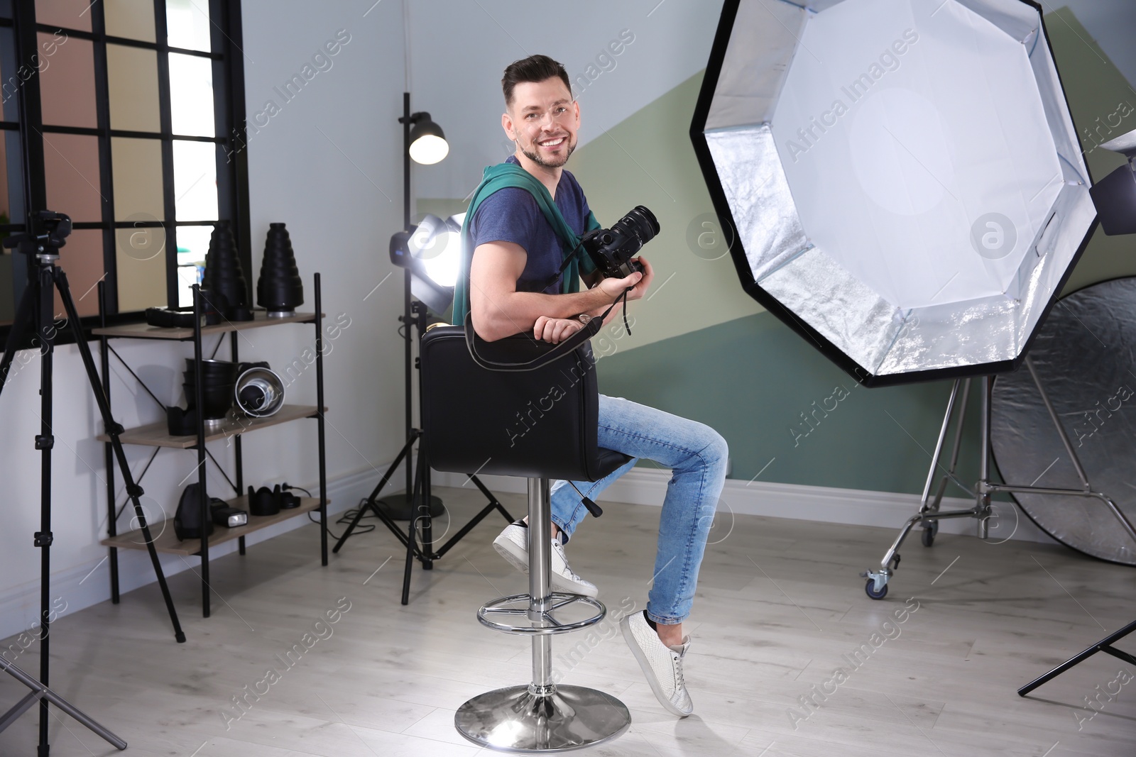 Photo of Professional photographer with camera and lighting equipment in studio