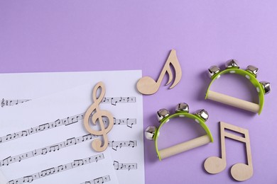 Photo of Tools for creating baby songs. Flat lay composition with wooden notes and tambourines for kids on violet background