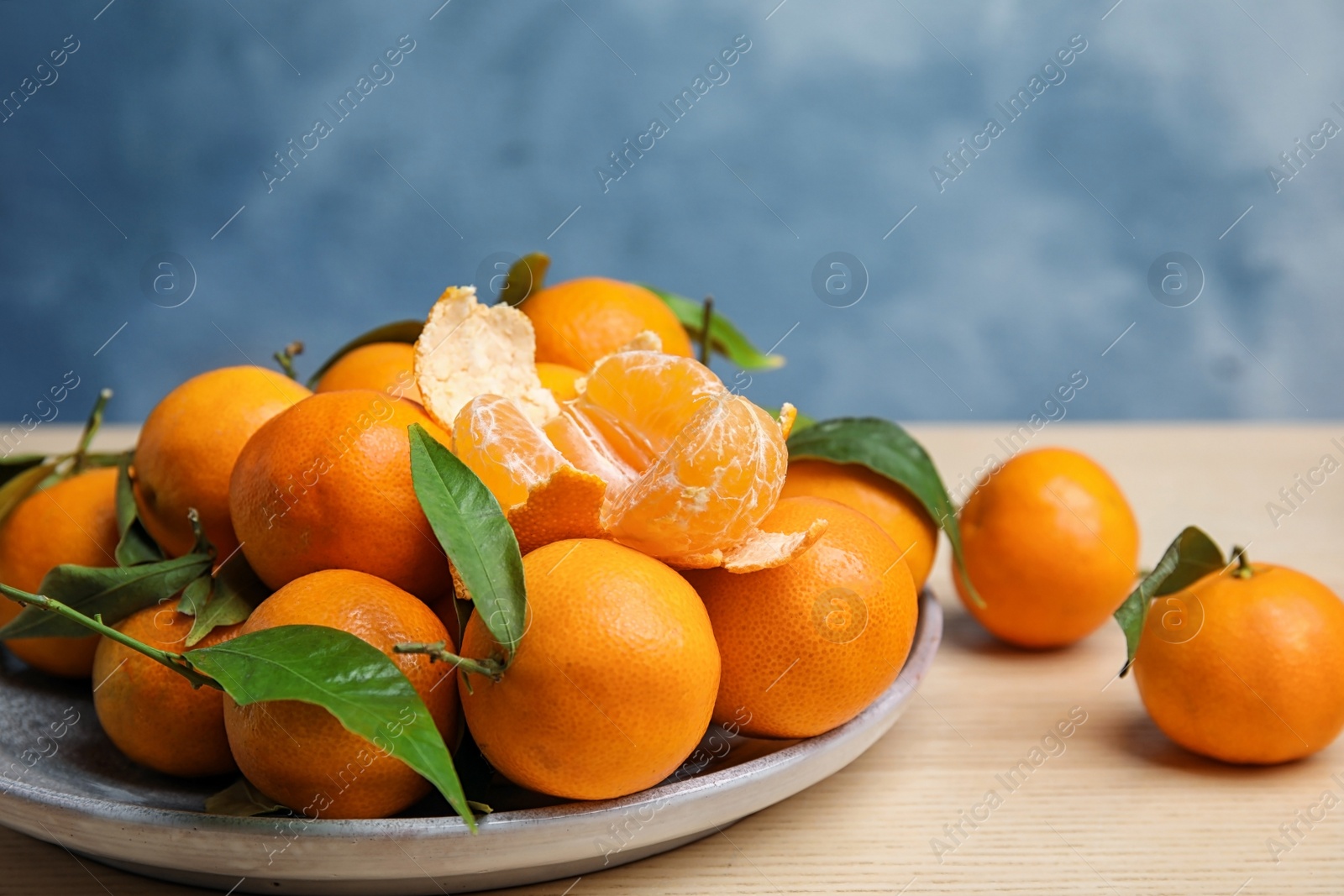 Photo of Plate with fresh ripe tangerines on wooden table