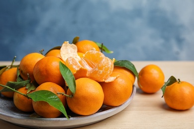 Plate with fresh ripe tangerines on wooden table