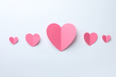 Pink paper hearts on white background, flat lay