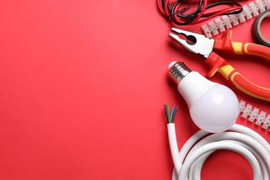 Set of electrician's tools and accessories on red background, flat lay. Space for text