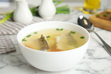 Delicious fish soup served on marble table, closeup