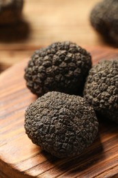 Photo of Black truffles with wooden board on table, closeup