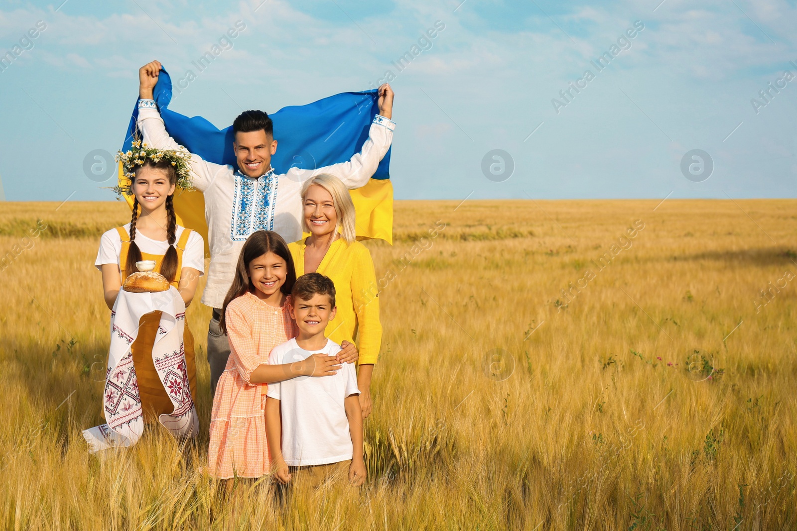 Photo of Happy family with national flag of Ukraine and treat in field. Space for text