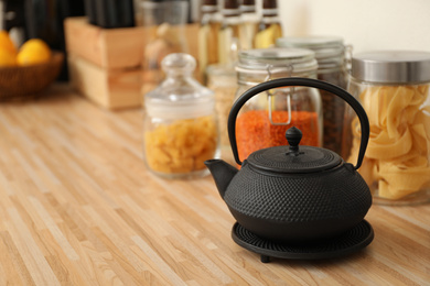 Photo of Black teapot on wooden countertop in kitchen, space for text. Interior element