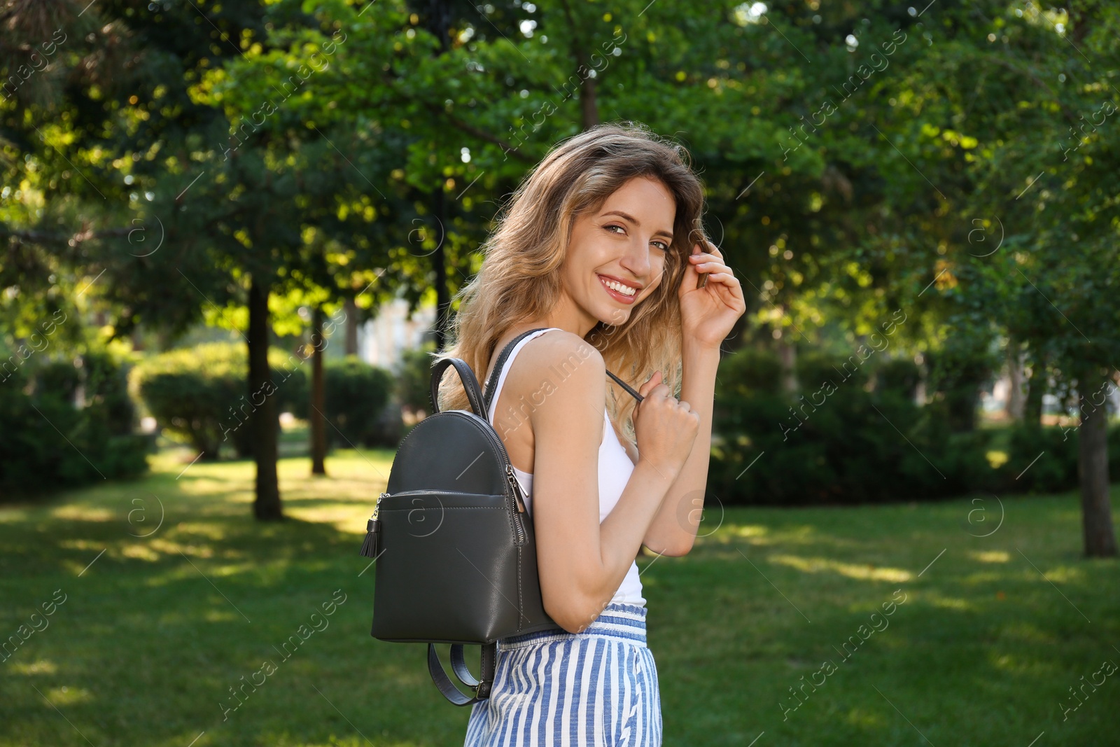 Photo of Young woman with stylish backpack in park