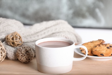 Photo of Cup of aromatic cacao on wooden table near window