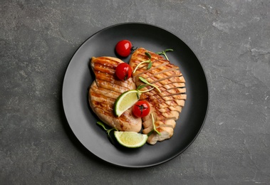 Photo of Tasty grilled chicken fillets with tomatoes, lime slices and green sprouts on grey table, top view