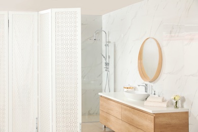 Photo of Modern bathroom interior with shower stall and folding screen